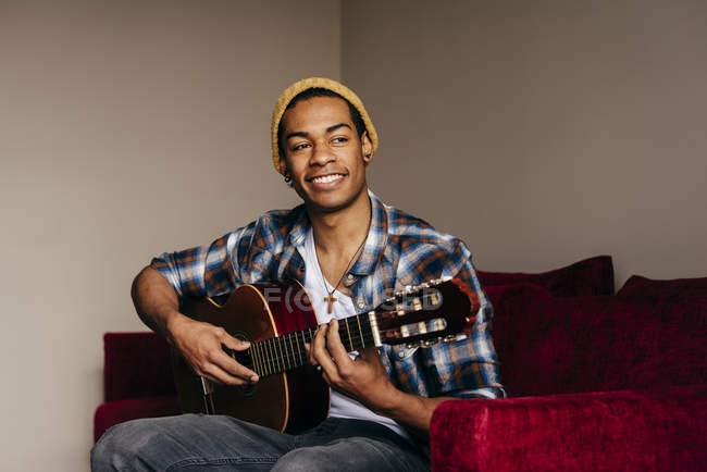 Fröhlicher Mann spielt zu Hause auf dem Sofa Gitarre — Stockfoto