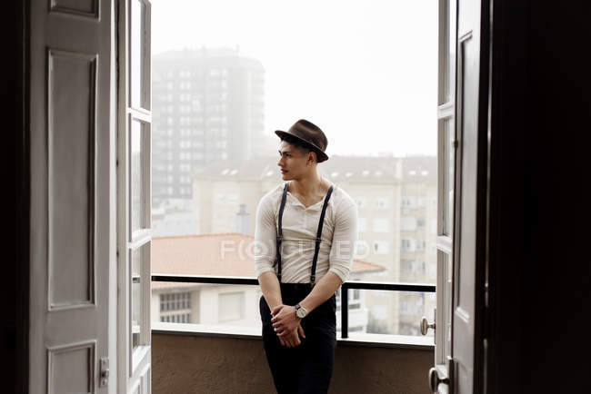 Stylish man leaning on balcony handrail and looking aside — Stock Photo
