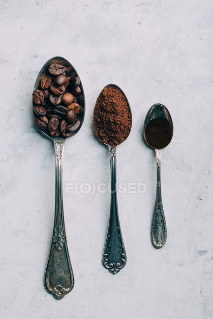 Granos de café, café molido y café negro en cucharas retro - foto de stock