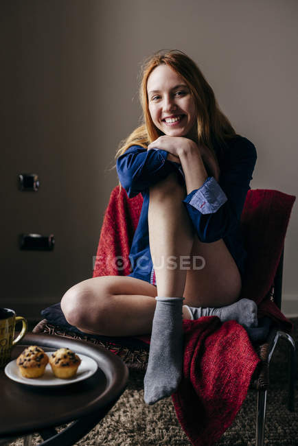 Sorrindo mulher posando em poltrona e olhando para a câmera — Fotografia de Stock