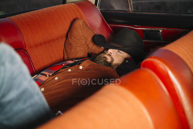 Зрелый мужчина в шляпе лежал и спал в винтажном автомобиле — стоковое фото