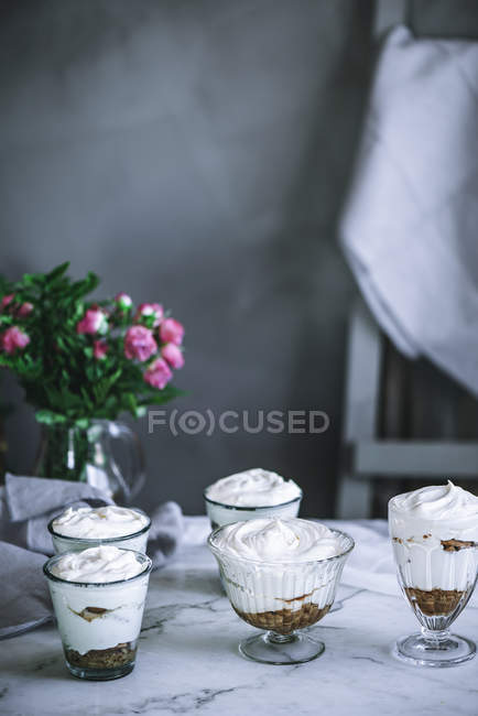 Still life of sweet panna cota desserts and bouquet of roses on table — Stock Photo