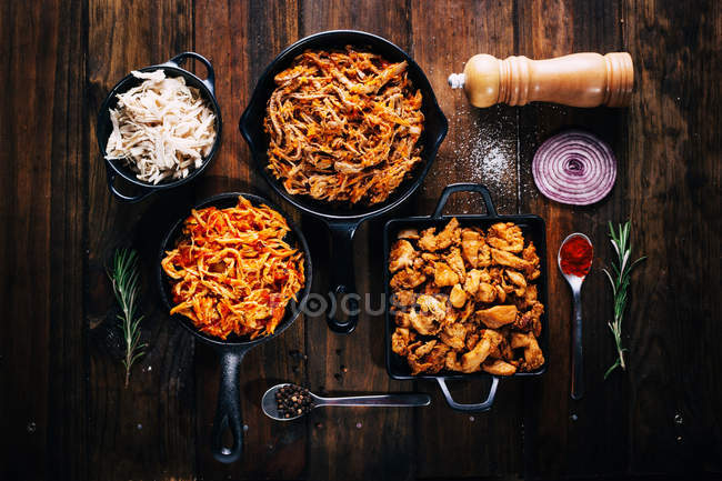 Arrangement of tasty dishes in frying pans on wooden table — Stock Photo