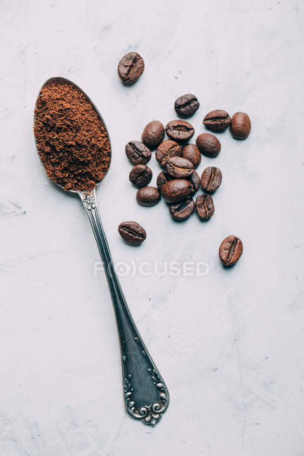 Directly above view of ground coffee in retro spoon by coffee beans — Stock Photo