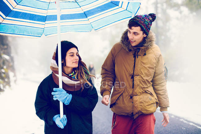 Пара з парасолькою, що йде по дорозі в лісі — стокове фото