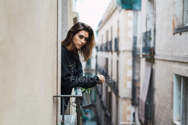 Bella donna appoggiata sul corrimano alla finestra e guardando la fotocamera . — Foto stock