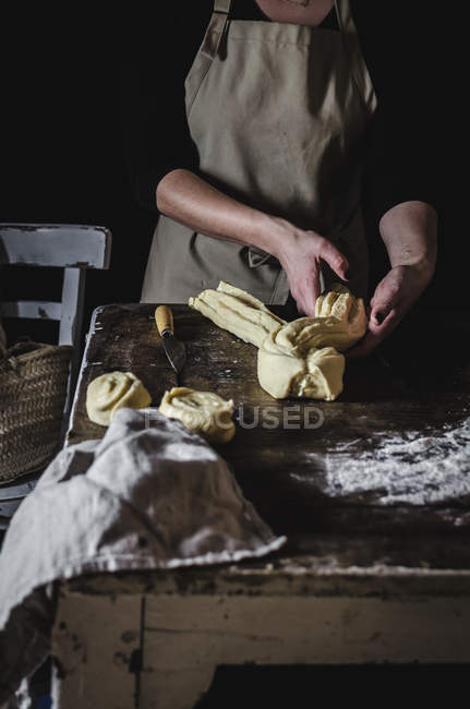 Sección media de la mujer haciendo pastelería dulce en la mesa de madera - foto de stock