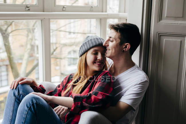 Zartes Paar umarmt sich auf Fensterbank mit geschlossenen Augen — Stockfoto