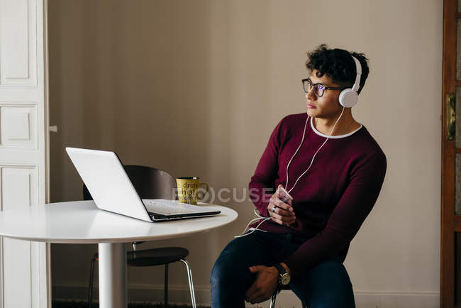 Young man in headphones looking at laptop — Stock Photo