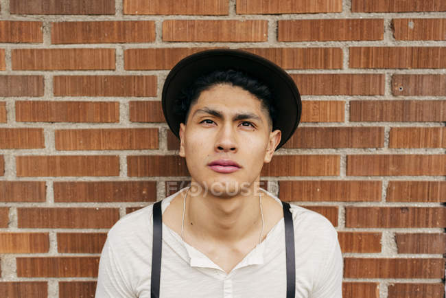 Sereno uomo in cappello posa al muro di mattoni — Foto stock