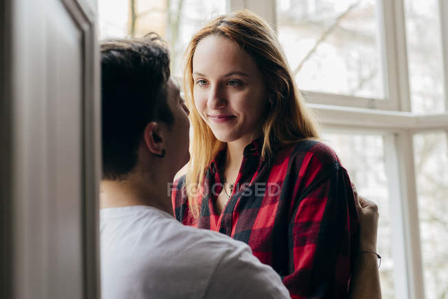 Young blonde girl sensually looking at boyfriend at window — Stock Photo