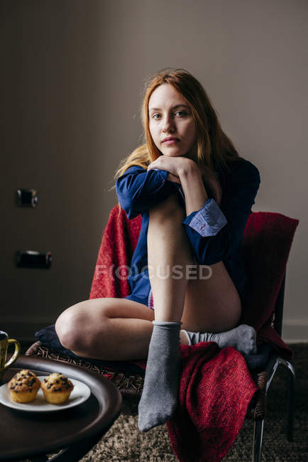 Pensive woman sitting in armchair and looking at camera — Stock Photo