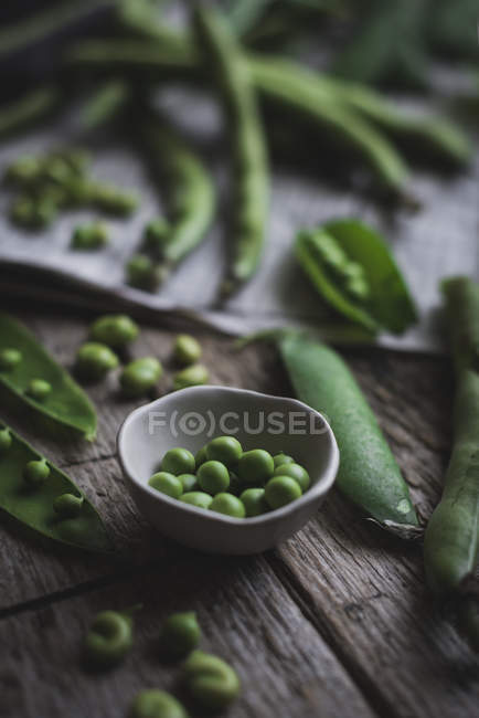 Grüne Erbsen in kleiner Keramikschüssel auf rustikalem Tisch — Stockfoto