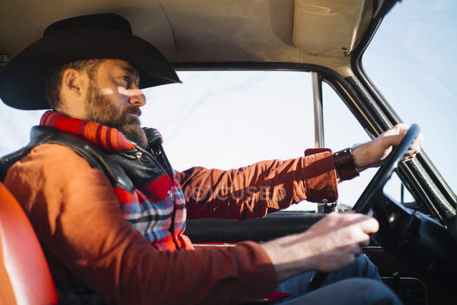 Side view of mature man in hat driving car in cloudless day. — Stock Photo