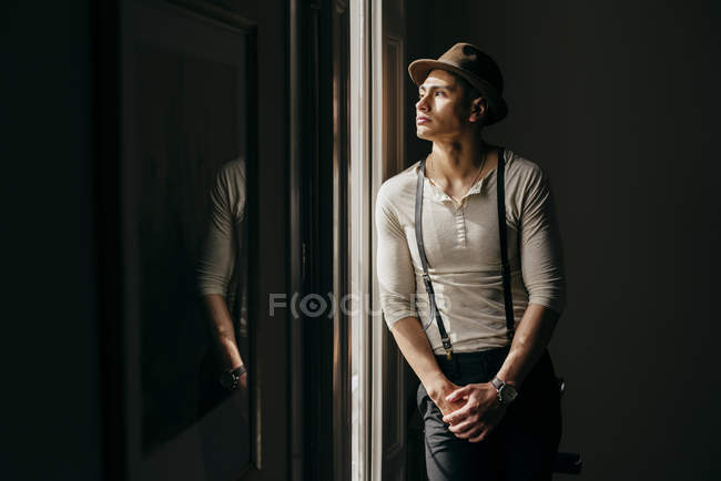 Мрійливий чоловік спирається на стіну і дивиться на вікно — стокове фото