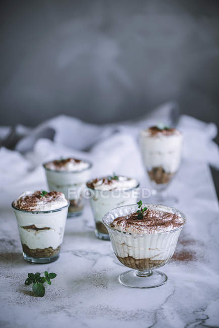 Gläser mit süßen cremigen Desserts, serviert mit Kakao auf dem Tisch. — Stockfoto