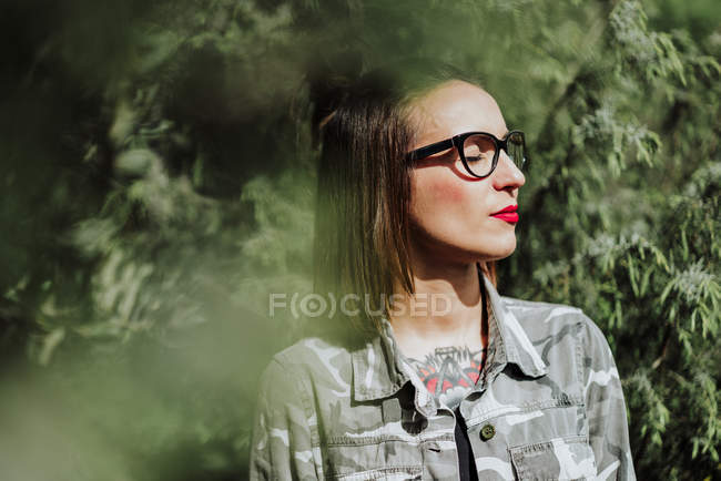 Mulher tatuada elegante em óculos posando na natureza — Fotografia de Stock