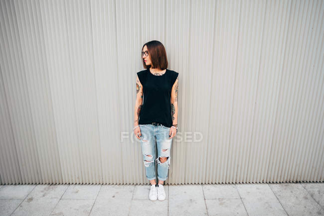 Front view of young woman standing at metal wall — Stock Photo