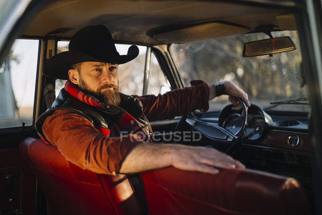 Barbudo hombre en sombrero posando en coche de época - foto de stock