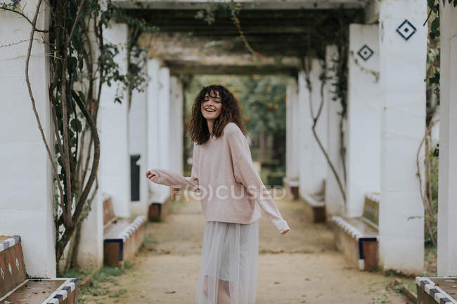 Щаслива жінка стрибає на парковій алеї і дивиться на камеру — стокове фото