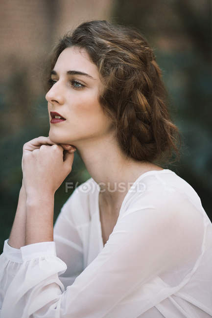 Portrait of brunette woman holding chin on hands and looking away — Stock Photo