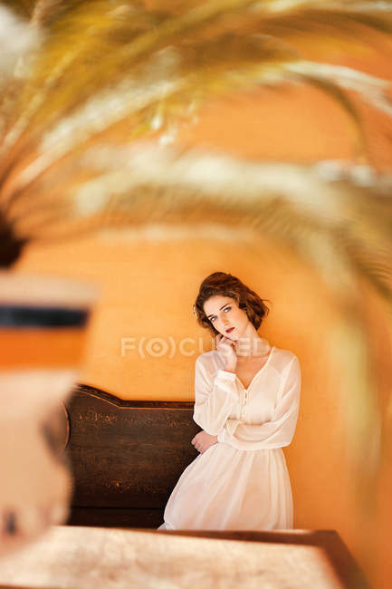 Woman in white dress sitting on bench and looking at camera — Stock Photo