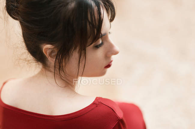 Vista posteriore della ragazza tenera in rosso guardando altrove — Foto stock