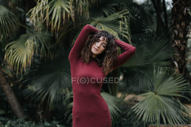 Bruna ragazza in posa con le mani sollevate su sfondo di foglie di palma . — Foto stock