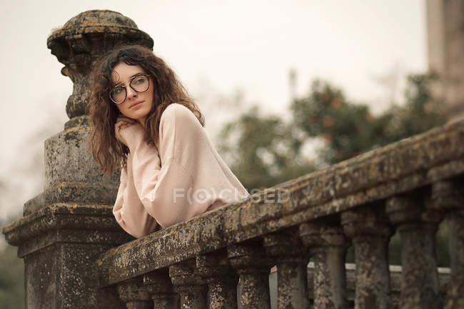 Pensive woman in glass leaning on ornate handrail and looking away — Stock Photo