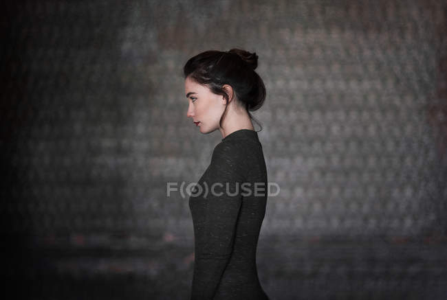 Side view of brunette in gray standing unemotionally — Stock Photo