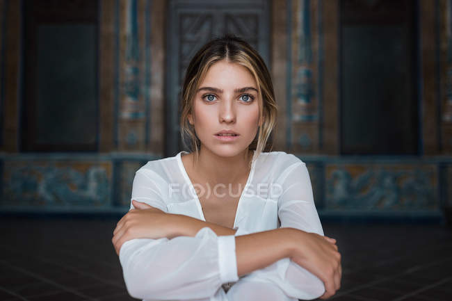 Sanftes Mädchen im weißen Kleid sitzt auf Stufen und blickt in die Kamera — Stockfoto