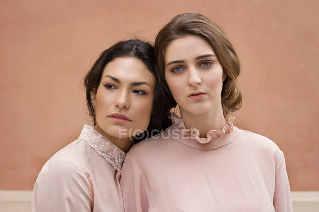 Frauen posieren gemeinsam gegen orangefarbene Wand — Stockfoto