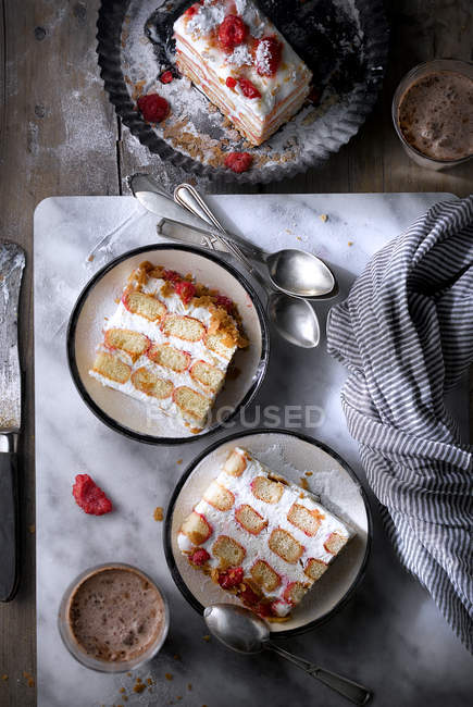 Tranches de gâteau aux framboises crémeux sur des assiettes — Photo de stock