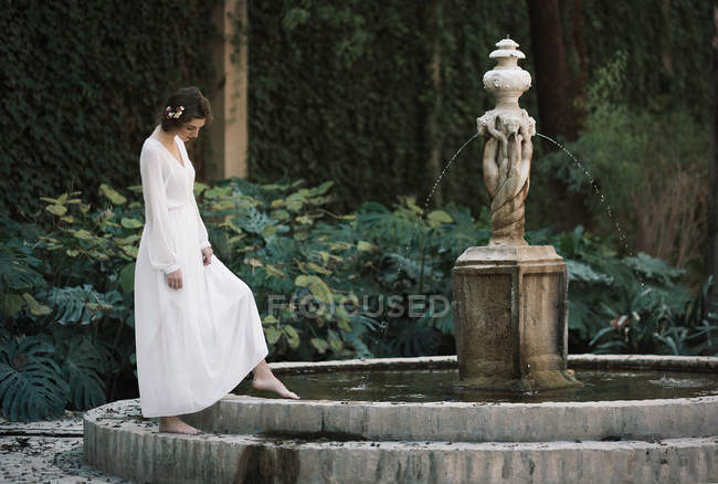 Брюнетка позирует у фонтана в парке — стоковое фото