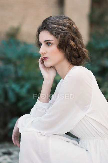 Seitenansicht der brünetten Frau im weißen Kleid — Stockfoto
