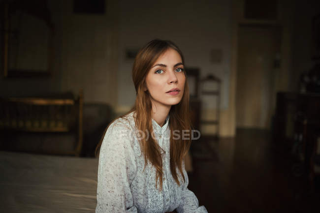Young woman sitting ob bedand looking at camera — Stock Photo