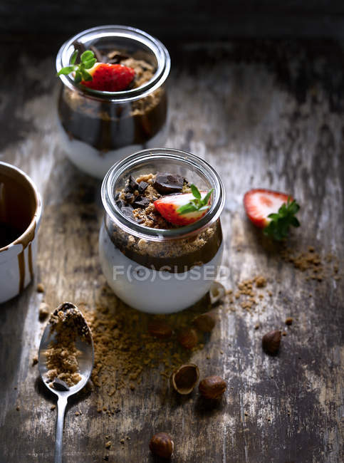 Frascos com morango e chocolate na mesa de madeira — Fotografia de Stock