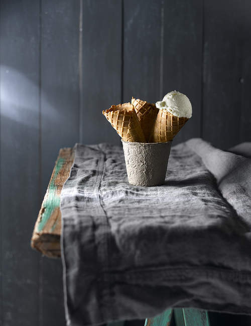 Натюрморт из вафельных рожков в кружке на деревенском столе — стоковое фото