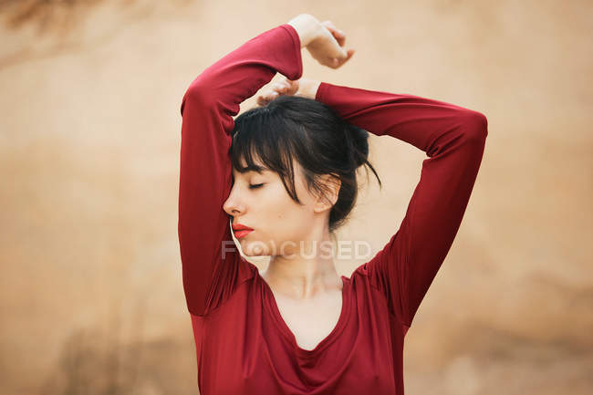 Sensual brunette posing with hands up and eyes closed. — Stock Photo