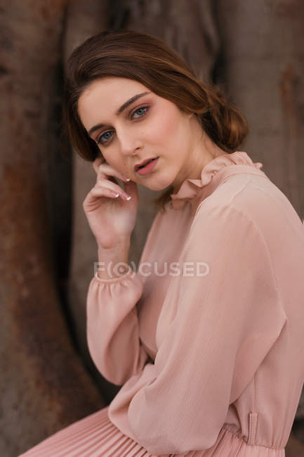 Woman in vintage clothes sitting by tree and looking at camera — Stock Photo