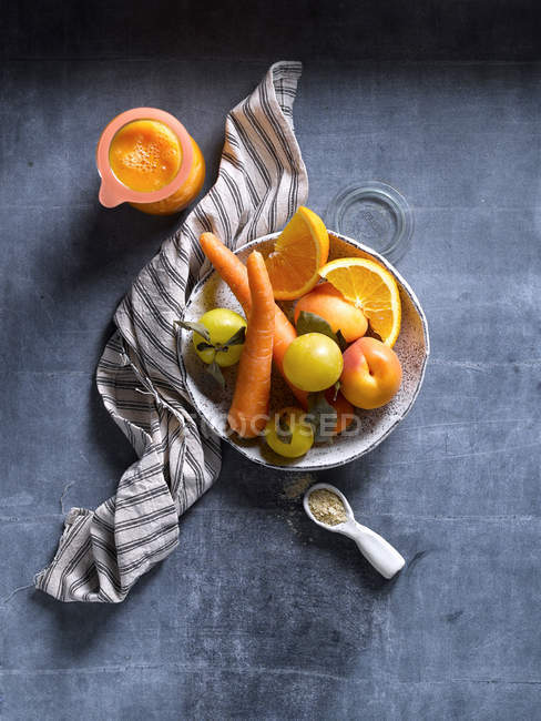 Натюрморт з апельсиновими фруктами та овочами на мисці на блакитному столі . — стокове фото
