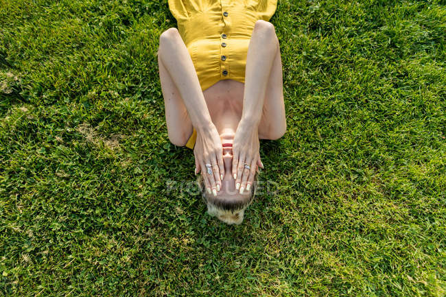 Жінка, що лежить на траві руками на обличчі — стокове фото