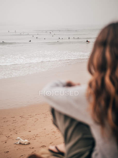 Женщина смотрит на серферов в океане — стоковое фото