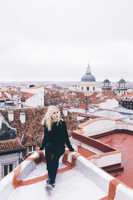 Blonde woman sitting on rooftop — Stock Photo
