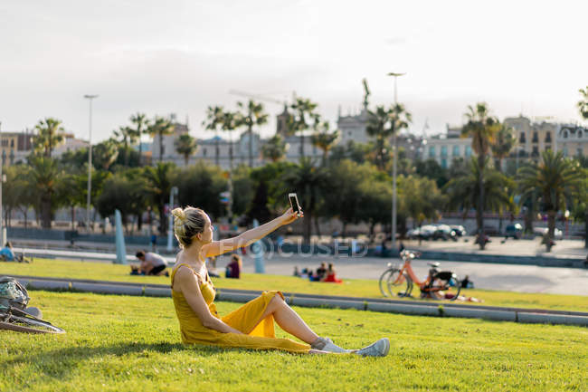 Жінка сидить на траві зі смартфоном — стокове фото