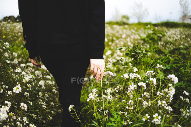 Mulher vestindo preto andando no campo verde — Fotografia de Stock