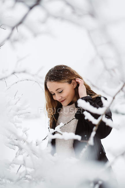 Frau steht zwischen winterlichen Ästen — Stockfoto
