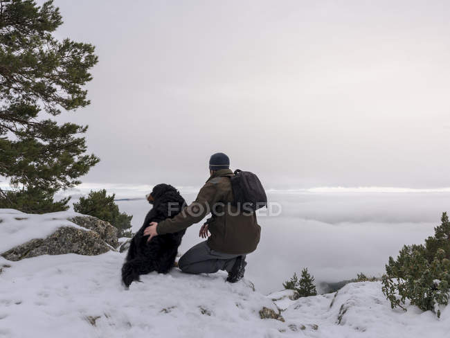 Senderista y perro en montañas nevadas - foto de stock