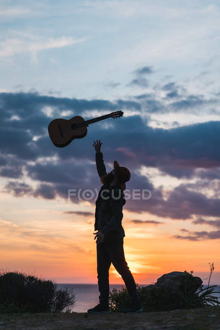 Man having fun with guitar on coast — Stock Photo