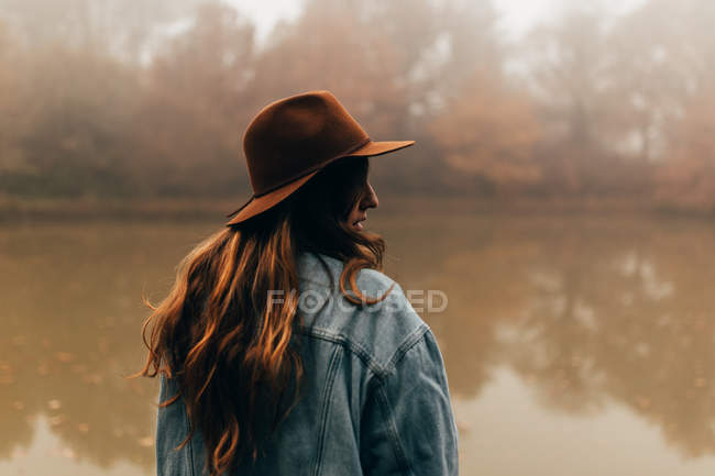 Femme portant un chapeau debout à l'étang — Photo de stock